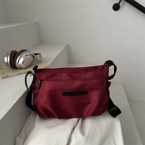 Lightweight multi-layer burgundy nylon crossbody bag for women on white steps