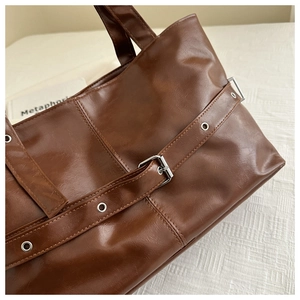 Close-up of vintage brown PU leather tote bag with buckle detail and metallic hardware