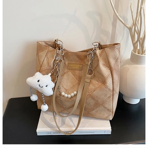 Detail of tan quilted tote bag with chain strap and cute white plush cloud charm