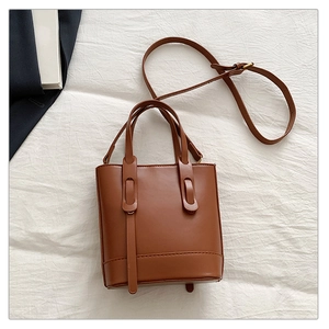 Vue détaillée du sac seau marron en cuir avec boucles de sangle au style vintage épuré