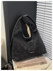 Detail of black matte leather tote bag with embossed logo on artistic book setting