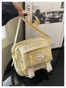 Detail of yellow nylon crossbody bag with buckle closure and brand label