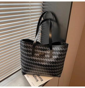 Detail of black tote bag featuring geometric wave patterns and premium leather handles
