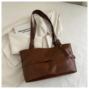 Detail of deep brown leather tote bag with metal buckle and decorative horizontal strap