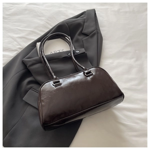 Detailed view of deep brown leather shoulder bag on a stylish grey blazer background