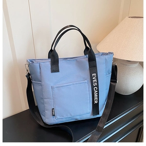 Detail of light blue canvas lunch bag featuring EVES CAMIER straps and front pocket
