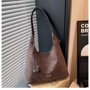 Dettaglio borsa a spalla in pelle marrone opaca con logo e tracolla lunga in cuoio