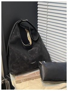 Macro shot of black suede tote bag texture with minimalist logo and matching leather pouch