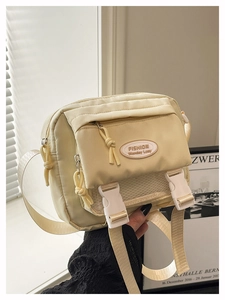 Detail of cream crossbody bag featuring white mesh pocket and adjustable shoulder strap