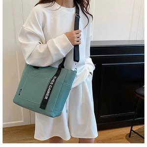Detail of teal canvas lunch bag with black EVES CAMIER straps and adjustable shoulder belt