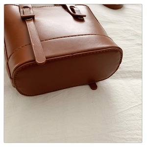 Vue détaillée du fond du sac seau en cuir marron caramel avec surpiqûres précises et brides