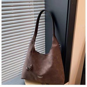 Dettaglio borsa hobo marrone con logo bianco e tracolla larga dalla trama opaca