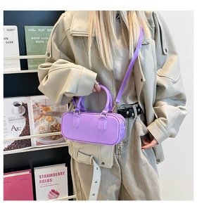 Macro shot of purple glossy mini jelly bag with golden metallic buckles and top handle
