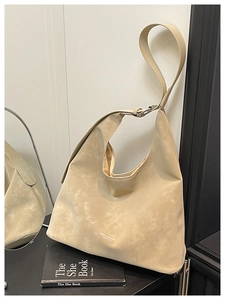 Detail of minimalist beige suede tote bag with adjustable strap and brand logo