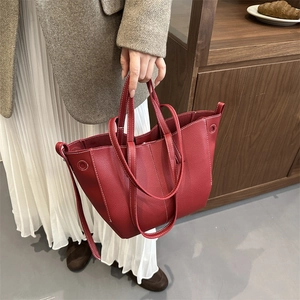Red lychee textured leather bucket bag with white contrast stitching and dual handles