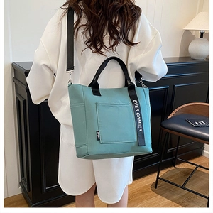 Rear view of mint green canvas lunch bag with black straps and adjustable shoulder strap