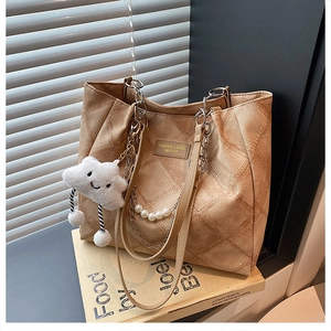 Detail view of khaki quilted tote bag featuring pearl strap, chain, and cloud charm
