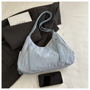 Detail view of light blue tote with wrinkled texture and stylish metal tassel zippers