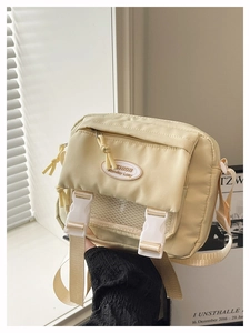 Detail of cute cream yellow canvas crossbody bag featuring dual buckles and wide shoulder strap
