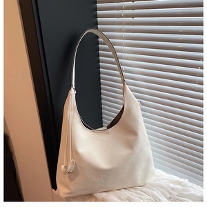 Dettaglio macro della borsa hobo in pelle bianco crema con logo e ciondolo a cuore