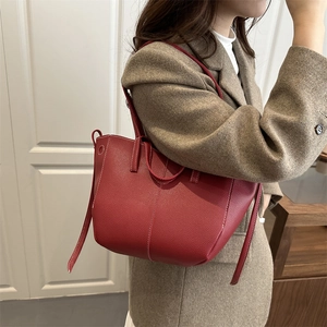 Deep red pebbled leather bucket bag with white contrast stitching and drawstring detail