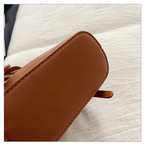 Gros plan sur les coutures précises et la texture de la base du sac marron caramel