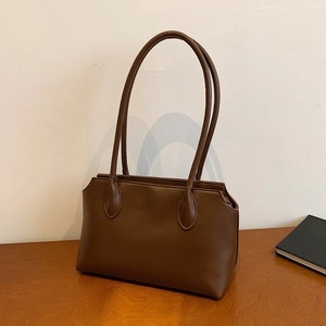 Minimalist brown vegan leather tote bag with long straps on a wooden table setup