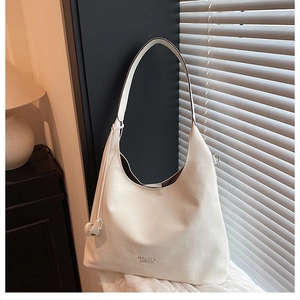 Dettaglio della borsa hobo bianca su tovaglia bianca con logo e luce naturale soffusa