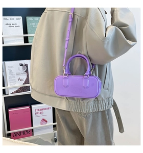 Detail of purple jelly cylinder bag with mirror finish and slim shoulder strap on a model