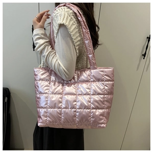 Detail view of pink metallic quilted tote bag worn by model, showing glossy texture and size