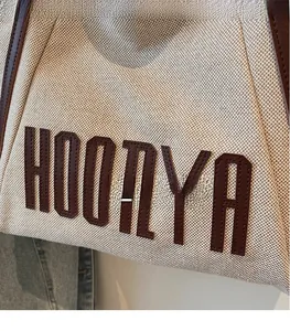 Detail of high-quality canvas tote bag showing brown leather logo patch and stitching