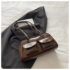 Detailed view of a vintage brown patent leather shoulder bag with dual front cargo pockets
