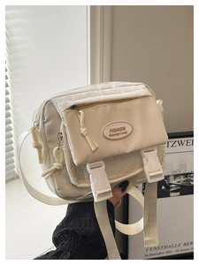 Detail of off-white nylon crossbody bag showing zippers, buckle, and mesh pockets