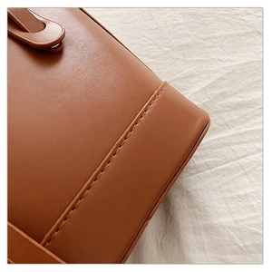 Gros plan des coutures précises sur le sac seau en cuir marron avec finition lisse