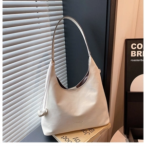 Dettaglio della borsa hobo minimalista in pelle crema con logo inciso su scena