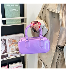 Detail of a purple patent leather square handbag with high-gloss finish and round handles