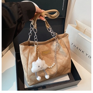 Detail of apricot quilted tote bag with silver chain handle and plush cloud charm