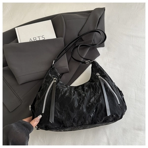 Close-up of black pleated texture shoulder bag with silver metal zipper details