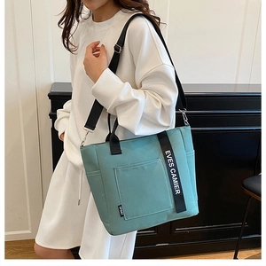 Close-up of mint green nylon tote lunch bag with black straps and shoulder strap detail