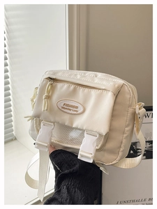 Detail of cream canvas messenger bag featuring plastic buckles and mesh pocket design