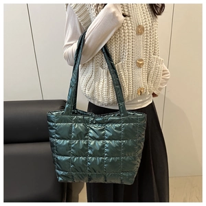 Detail of dark green quilted tote bag featuring metallic finish and square stitching