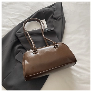 Detail of a brown vintage leather shoulder bag resting on a dark blazer and white linen