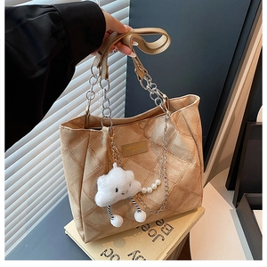 Detail of quilted tote bag featuring silver chain strap and plush cloud charm accessory