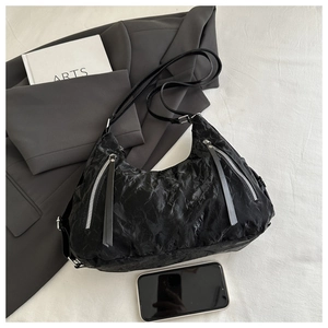 Close-up of black wrinkled texture hobo bag with silver zipper detail on white background