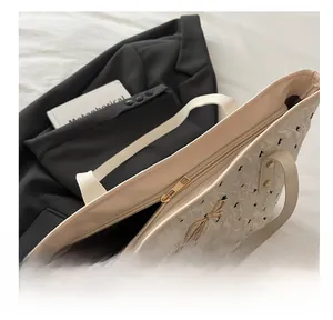 Detail showing the smooth gold metal zipper and bow hardware on the pleated tote bag