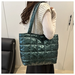 Detail of dark green quilted tote bag showing puffer texture and wide shoulder strap