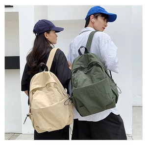 Detail of couple wearing minimalist nylon backpacks with drawstring side pockets and large capacity