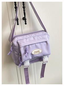 Detail of lavender purple nylon crossbody bag with white buckles and fashion label