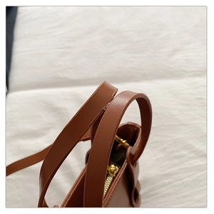 Détail d'un sac à main en cuir PU marron avec doubles poignées et fermeture éclair dorée