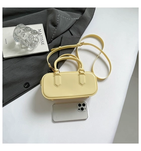 Pale yellow leather handbag with phone for scale on a minimalist art lifestyle backdrop